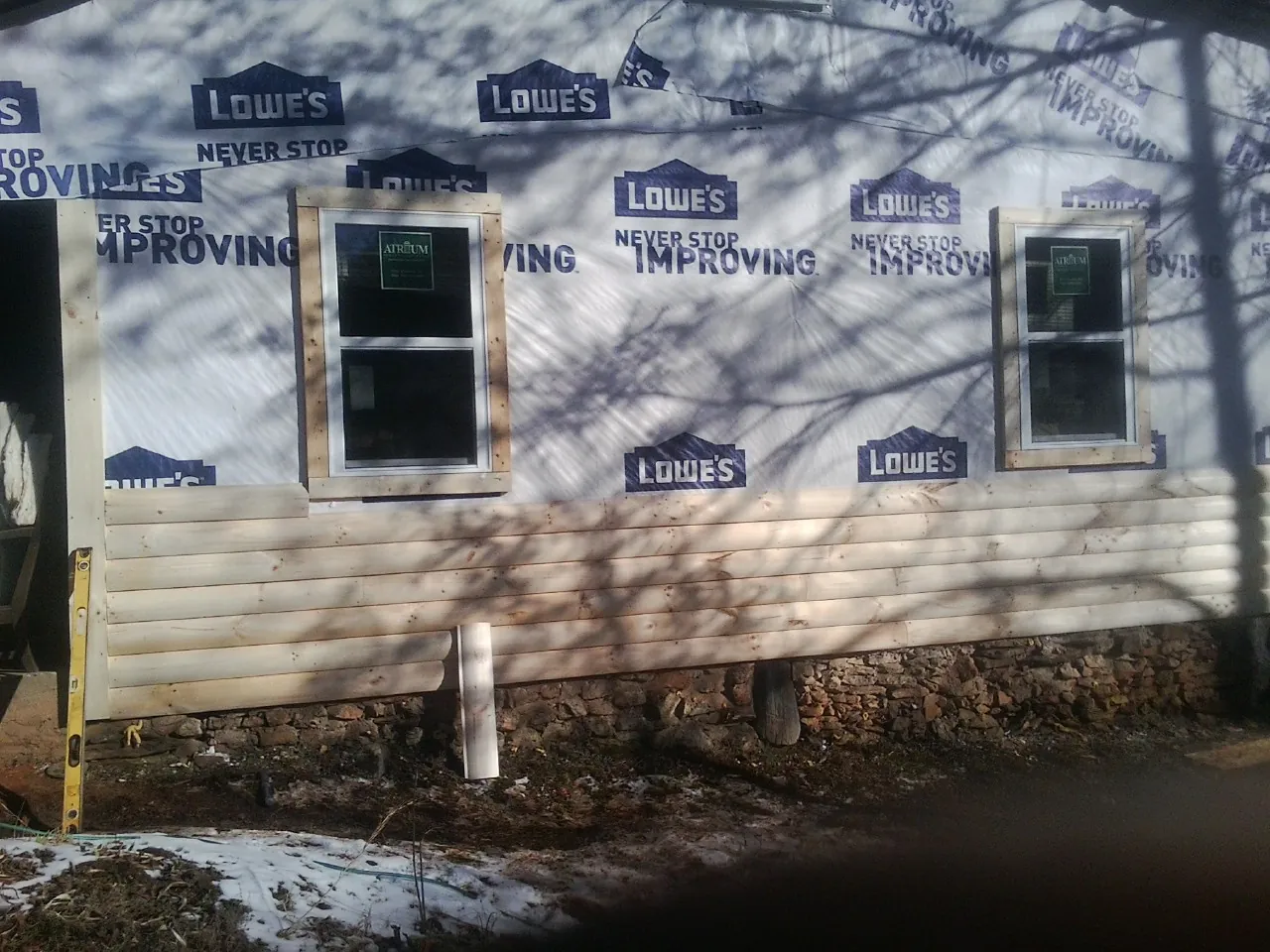 House wrap and new log siding going up on an exterior wall in Coward