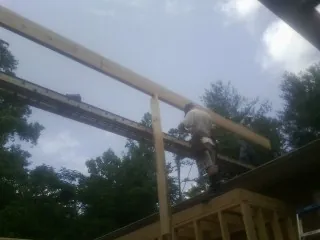 Carpenter setting a ridge beam over a new addition frame — Ice Dam Removal by Roofing Brothers in Coward