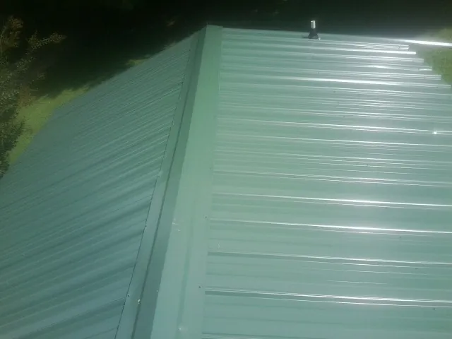 New green metal panels meeting at the ridge of a roof — Flat Roof Repair work by our crew in Coward