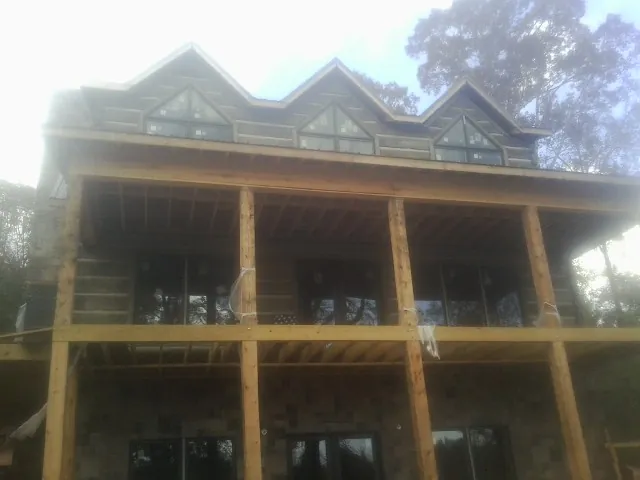 Dormers and porch framing on a large log home under construction — Roof Coating work by our crew in Coward