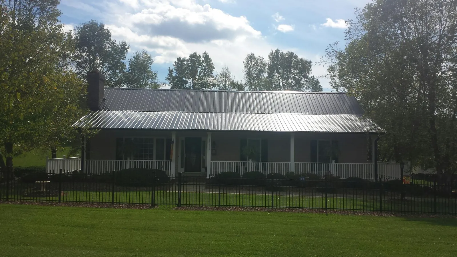 Gray metal roof on a brick ranch with a full width front porch — Gutter Guard Installation work by our crew in Coward