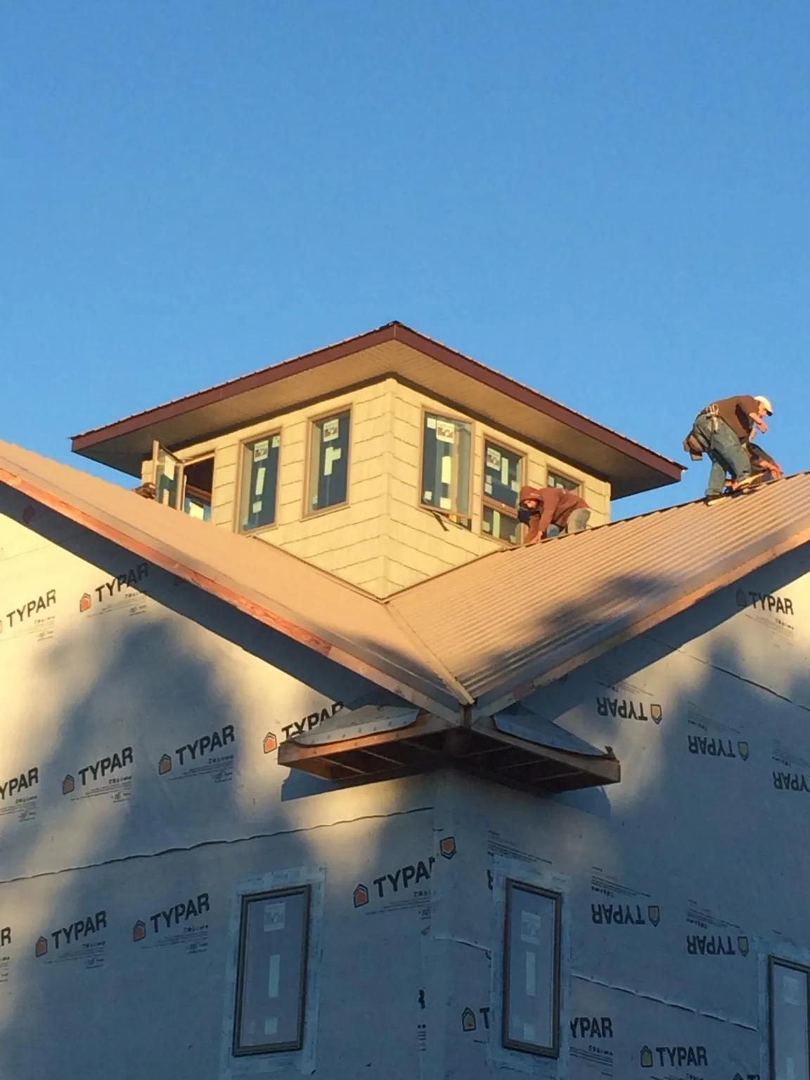 Roofers working around a rooftop cupola on a new metal roof at sunset — Roof Waterproofing in Coward by Roofing Brothers